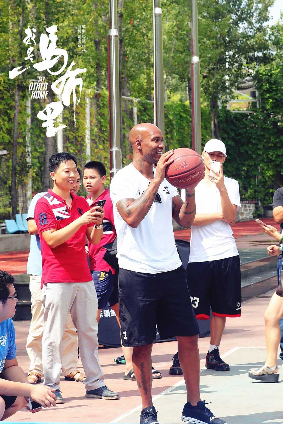 马布里身穿休闲装站在孩子们中间，脸上挂着慈父般的笑容，仿佛一位邻家大叔叔正准备给小朋友们上一堂别开生面的篮球课。