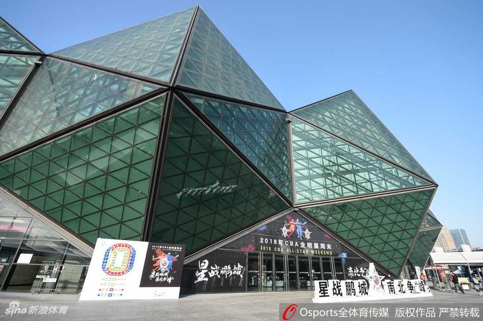 夜幕降临，华灯初上的大运中心体育馆犹如一颗璀璨的水晶，蓝色的灯光与周围的路灯交相辉映，倒映在平静的水面上，美轮美奂，充满了现代感。