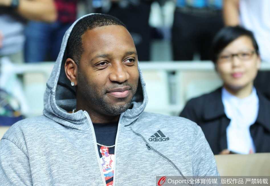 麦蒂的侧脸特写，轮廓分明，他微微侧身看向球场另一侧，背景是虚化的观众席和灯光，营造出一种虽置身人群却独享回忆的宁静感。