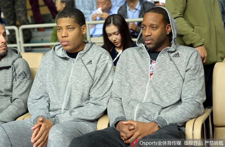 赛场上的拼抢异常激烈，球员们汗如雨下，而麦蒂坐在场边仿佛一个安静的观察者，眼前的喧嚣与他沉静的气质形成鲜明对比。