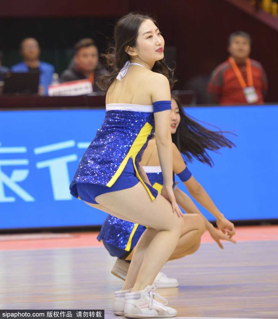 一名篮球宝贝在表演中高高跃起，裙摆飞扬，犹如冬日里的一团火焰，她的每一个细胞都在随着音乐的节拍律动。