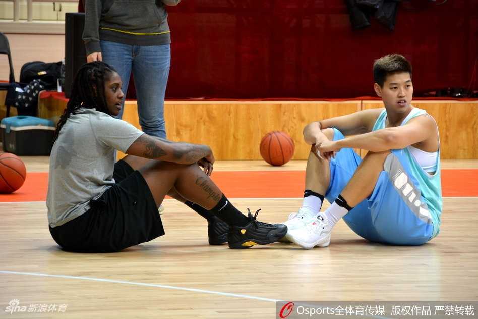 山东女篮队员们正在体能教练的指导下进行核心力量训练，汗水浸湿了球衣，眼神中透露出坚定与渴望。